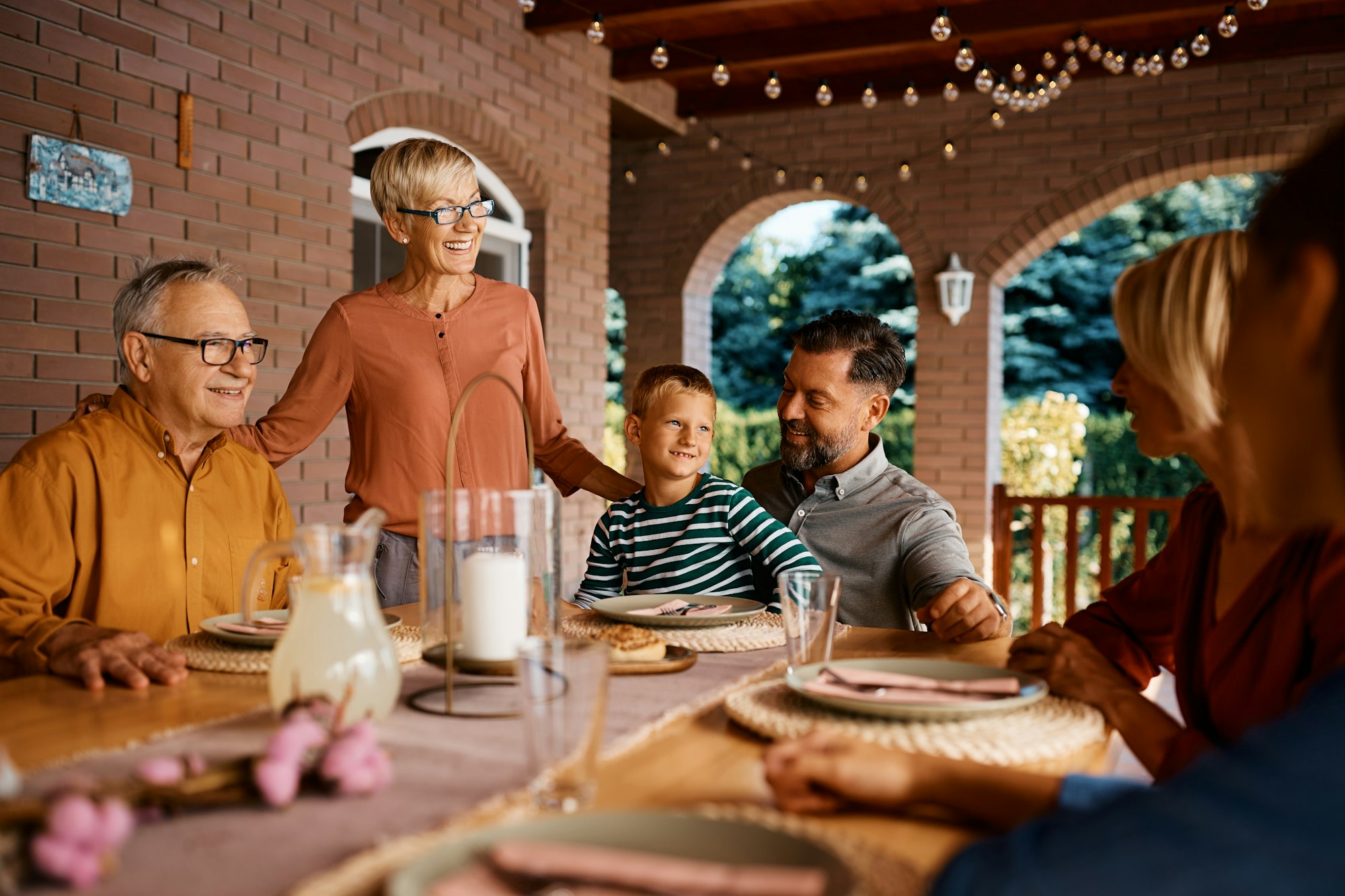 Happy extended family talking while gathering at dining table on a patio.