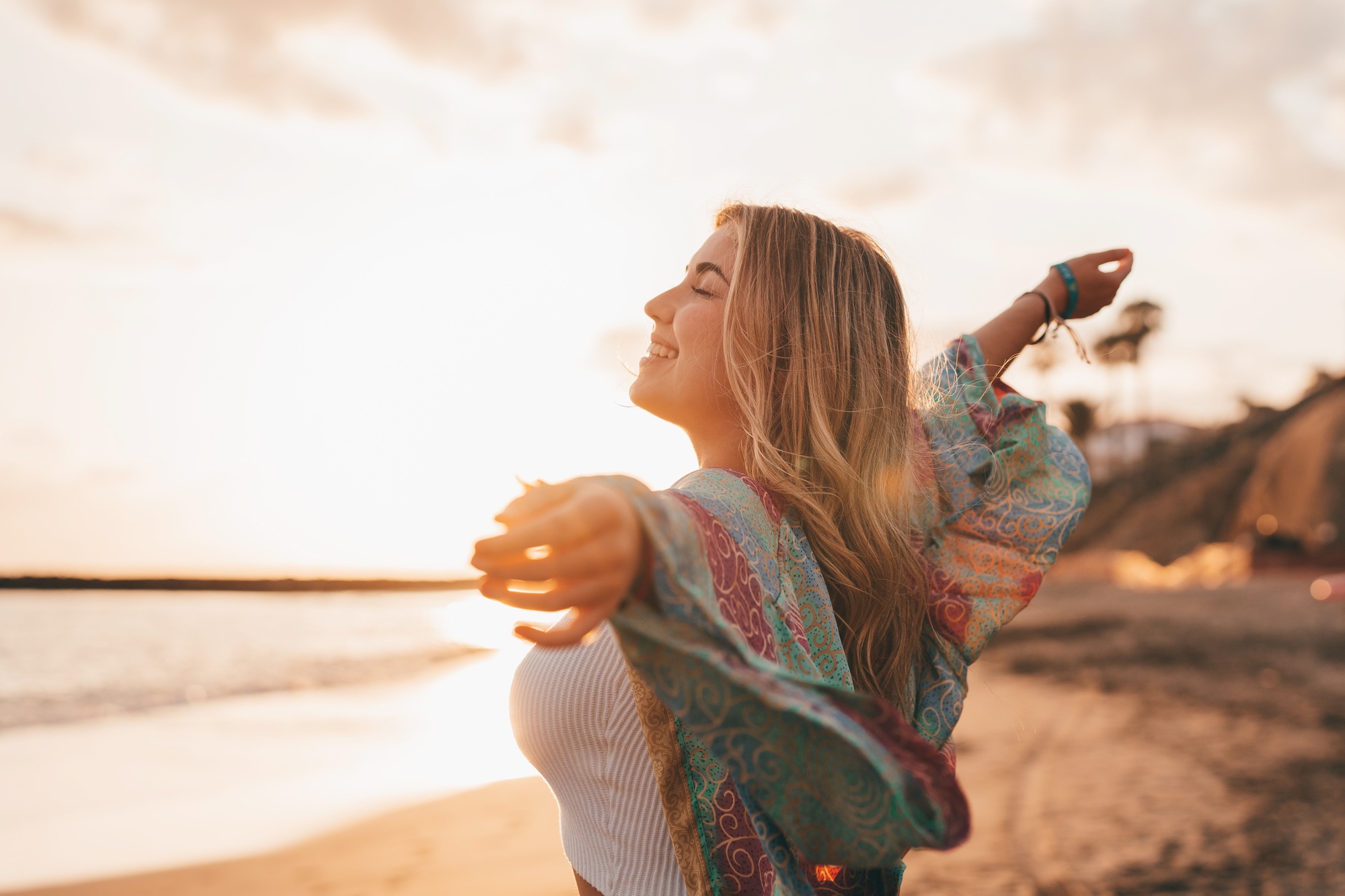 Portrait of one young woman at the beach with openened arms enjoying free time and freedom